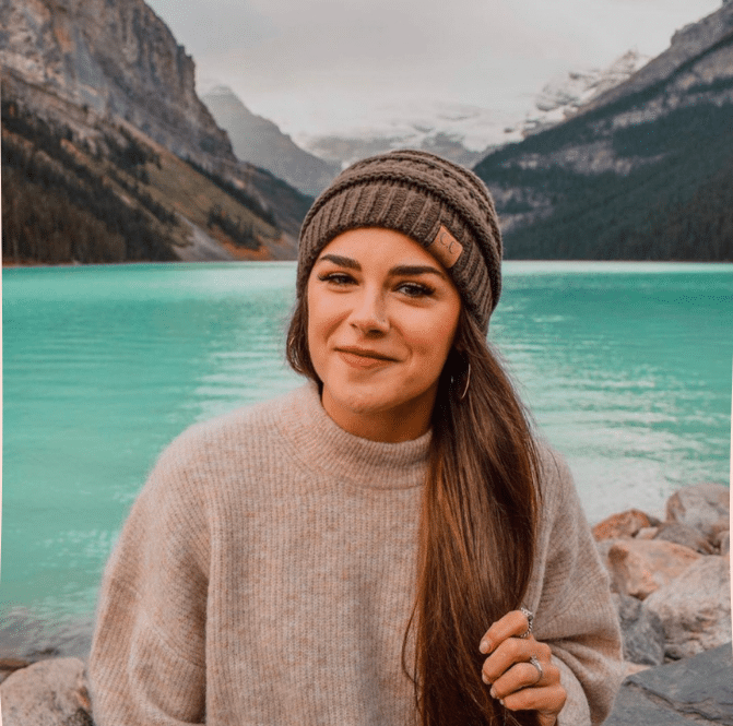 woman with long hair, wearing a knit hat and smiling