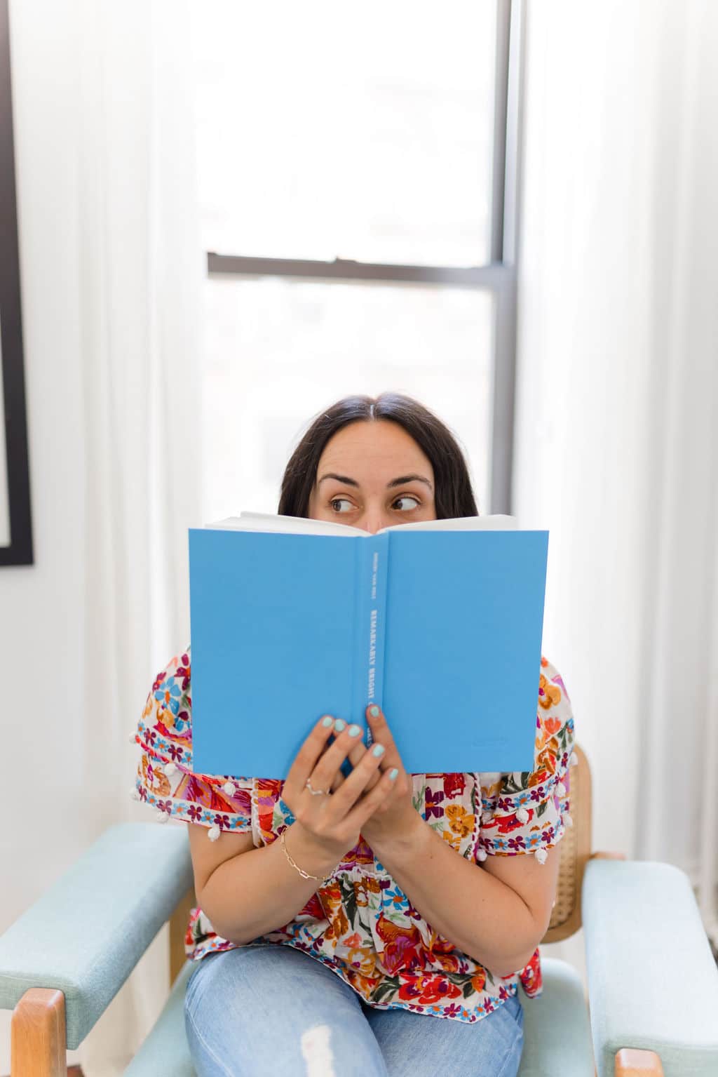woman with dark hair holding a book up to her face