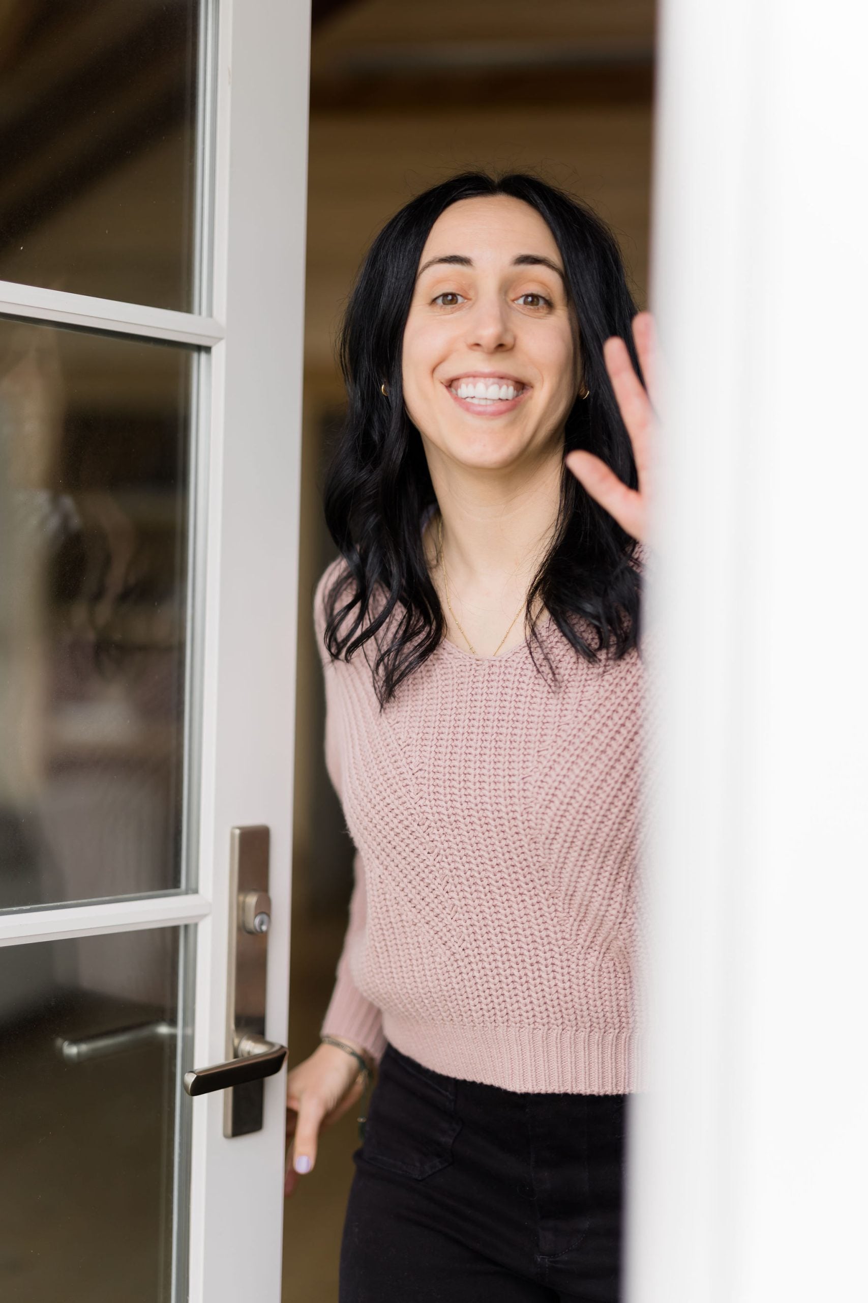 woman with dark hair smiling and waving hello