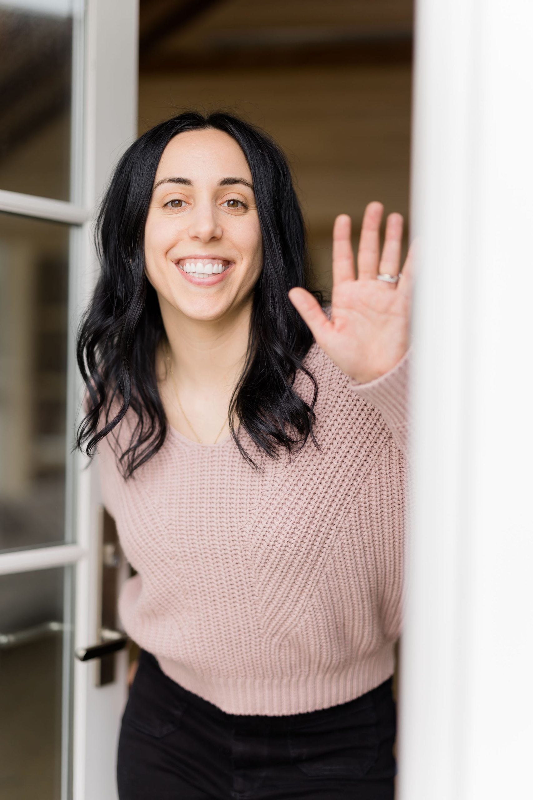 woman with dark hair smiling and waving hello