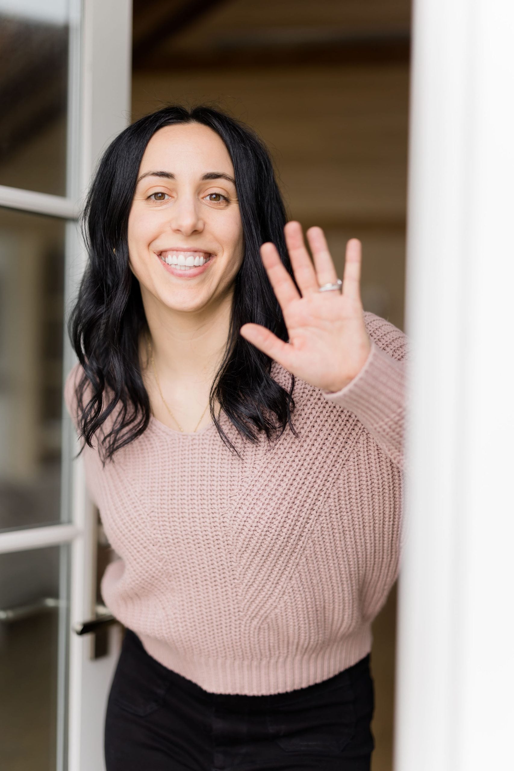 woman with dark hair smiling and waving hello