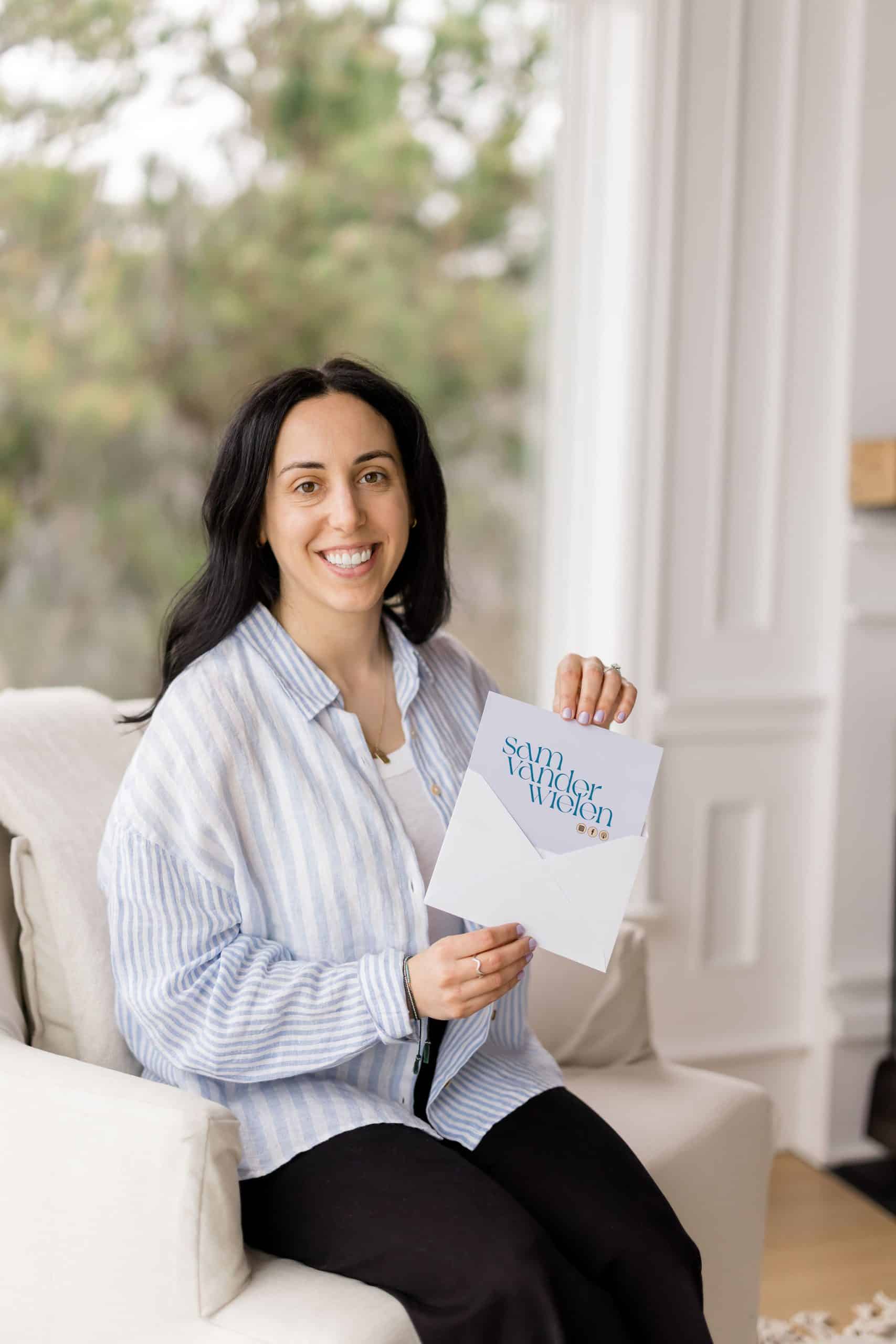 women wearing a blue shirt sitting in a chair pulling a card out of an envelope