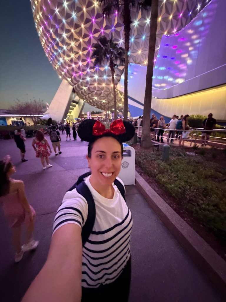 Sam Vander Wielen wearing minnie ears standing in front of Epcot
